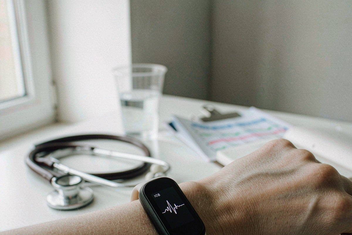 Medical-grade wrist wearable showing a heart-rate reading on a clinic desk