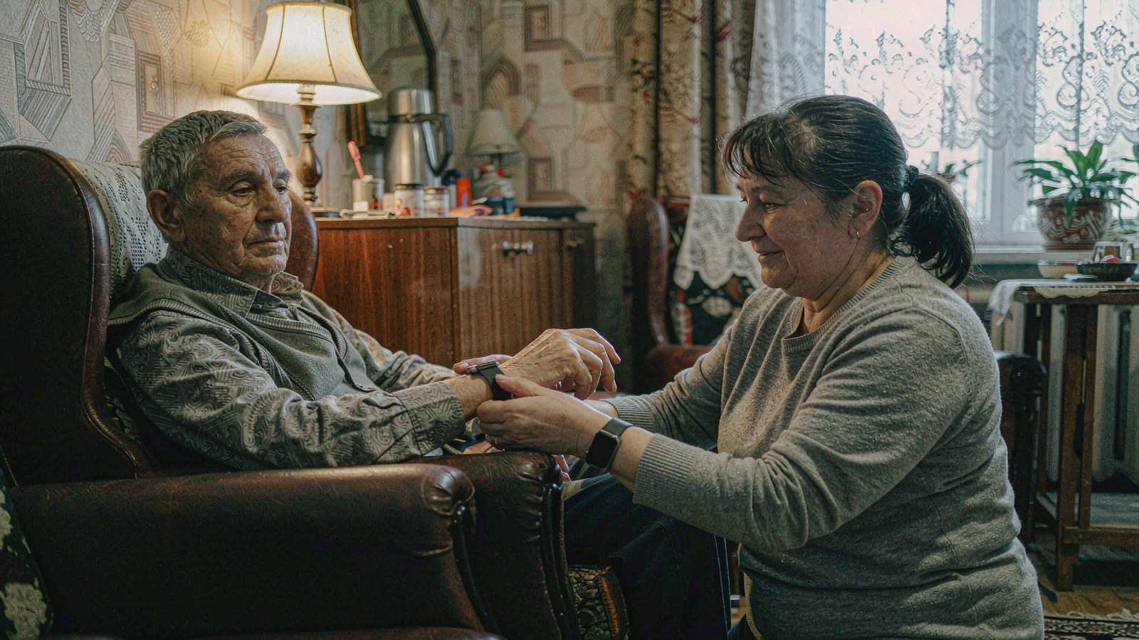 Caregiver helping an elderly patient wear a vital-signs wearable